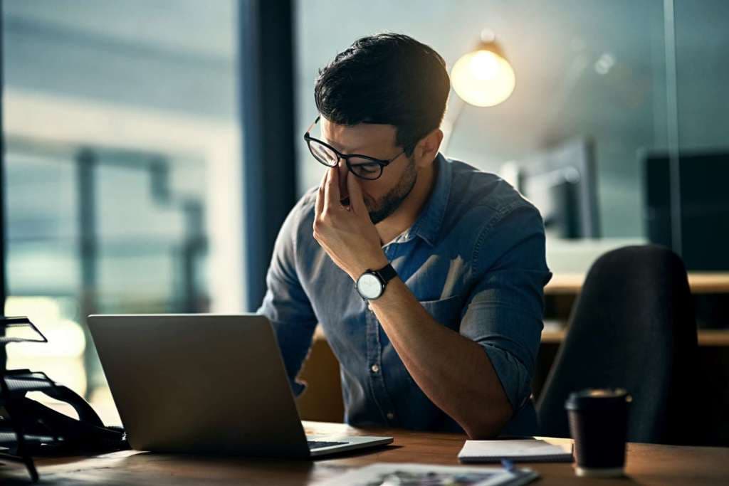 Aufnahme eines jungen Geschäftsmannes, der während einer langen Nacht bei der Arbeit unter Stress steht