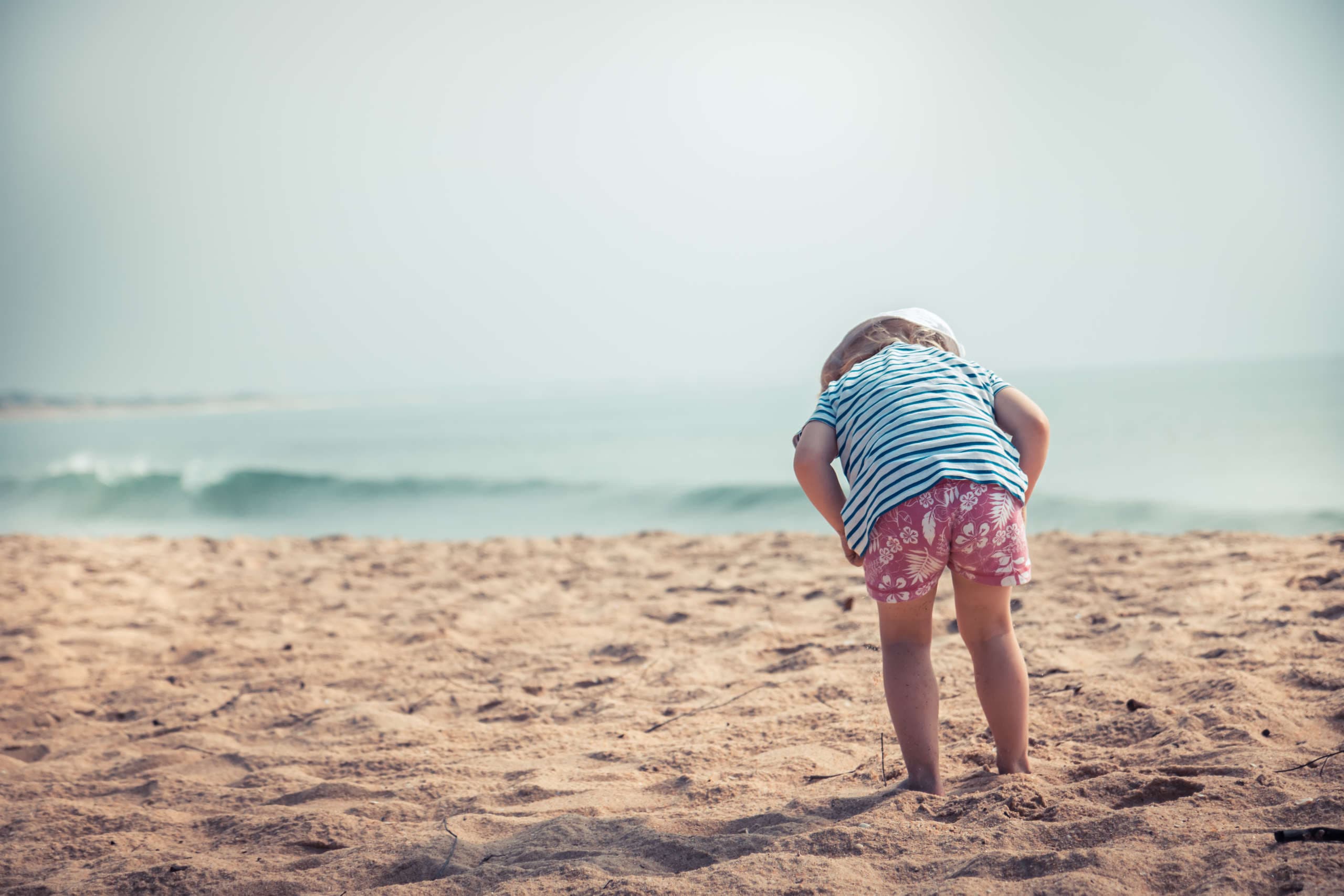 An einem Sonnentag am Meer schützen Hut und Kleidung vor Sonennbrand