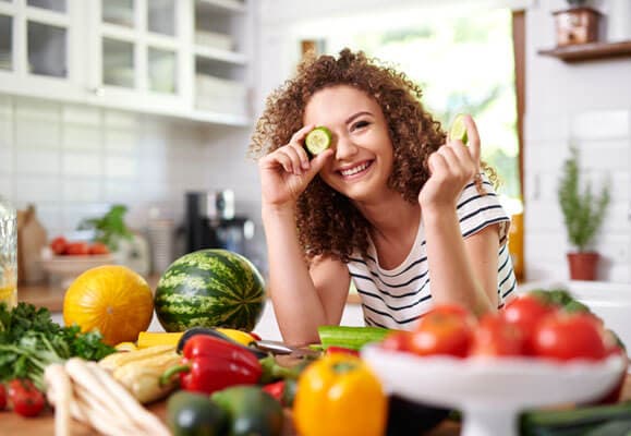 Woman holding a slice of cucumber