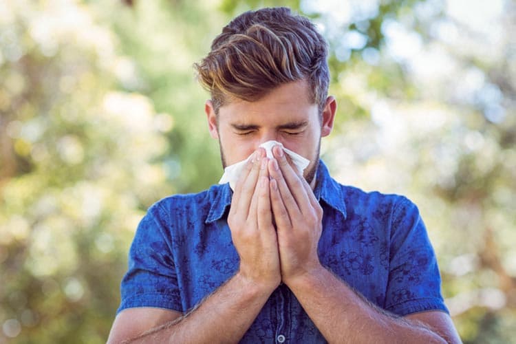Handsome hipster blowing his nose on a sunny day