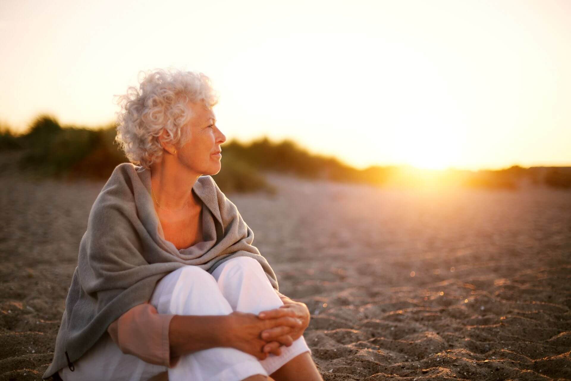Ältere Dame sitzt am Strand