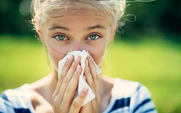 Portrait of teenage girl blowing her nose on a summer day. The girl is allergic to the pollen.Nikon D850