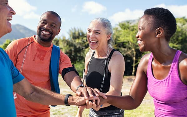 Ältere, sportliche Leute legen draussen Hände aufeinander nach Workout