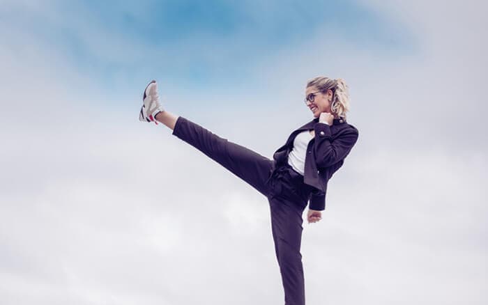 Junge Frau tritt als Zeichen von Stärke und Sucht. Im Hintergrund der blaue Himmel. Kick it like a lady Konzept.