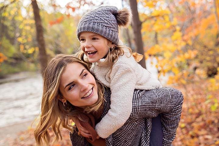 A Little girl and her mother playing in the autumn park
