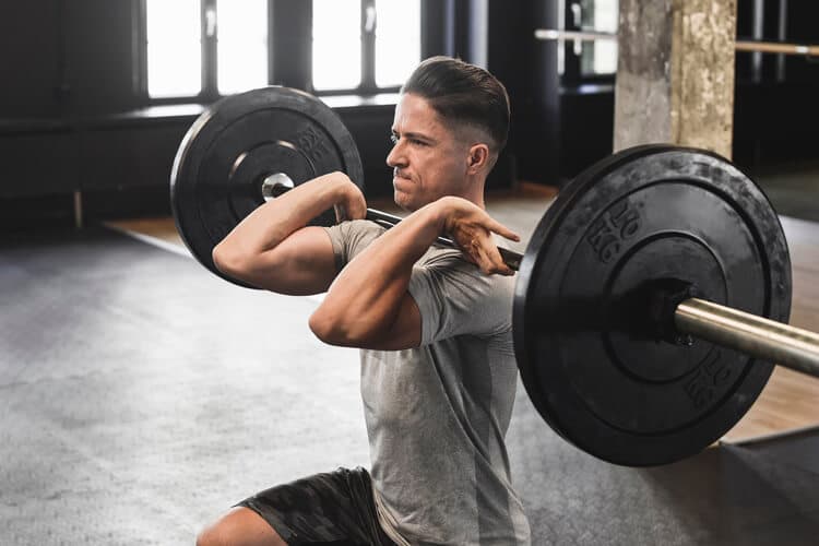 Junger Mann im Fitnessstudio beim Langhantel-Krafttraining