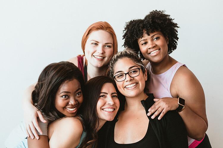 Eine Gruppe junger, fröhlicher Frauen in Sportkleidung.