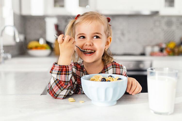 Kleines Mädchen glücklich beim Frühstück in der Küche