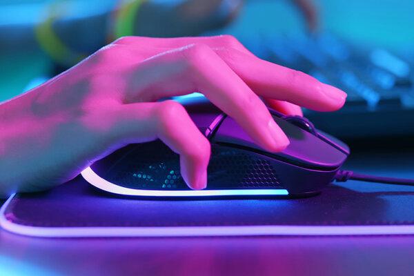 Farbig beleuchtete Hand auf PC-Maus