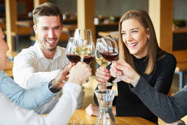 Junge Leute stossen mit einem Glas Wein an.