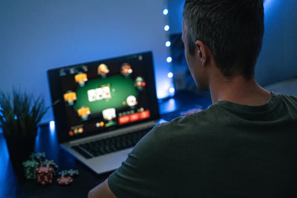 Mann sitzt im Dunkeln vor dem Laptop und spielt Online-Poker
