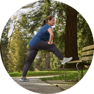 Frau im Jogginganzug mit Diabetes und FreeStyle Libre stretcht ihre Beine an einer Parkbank.